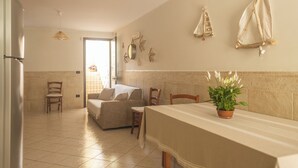 Un'ampia zona giorno con tavolo da pranzo, sedie, divano e una pianta in vaso.