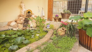Un giardino con uno stagno, piante e decorazioni.