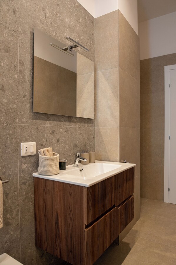 A modern bathroom with a large mirror, wooden vanity, and a towel rack.