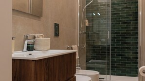 Un bagno moderno con un mobile vanitario in legno, un water bianco e una cabina doccia in vetro.