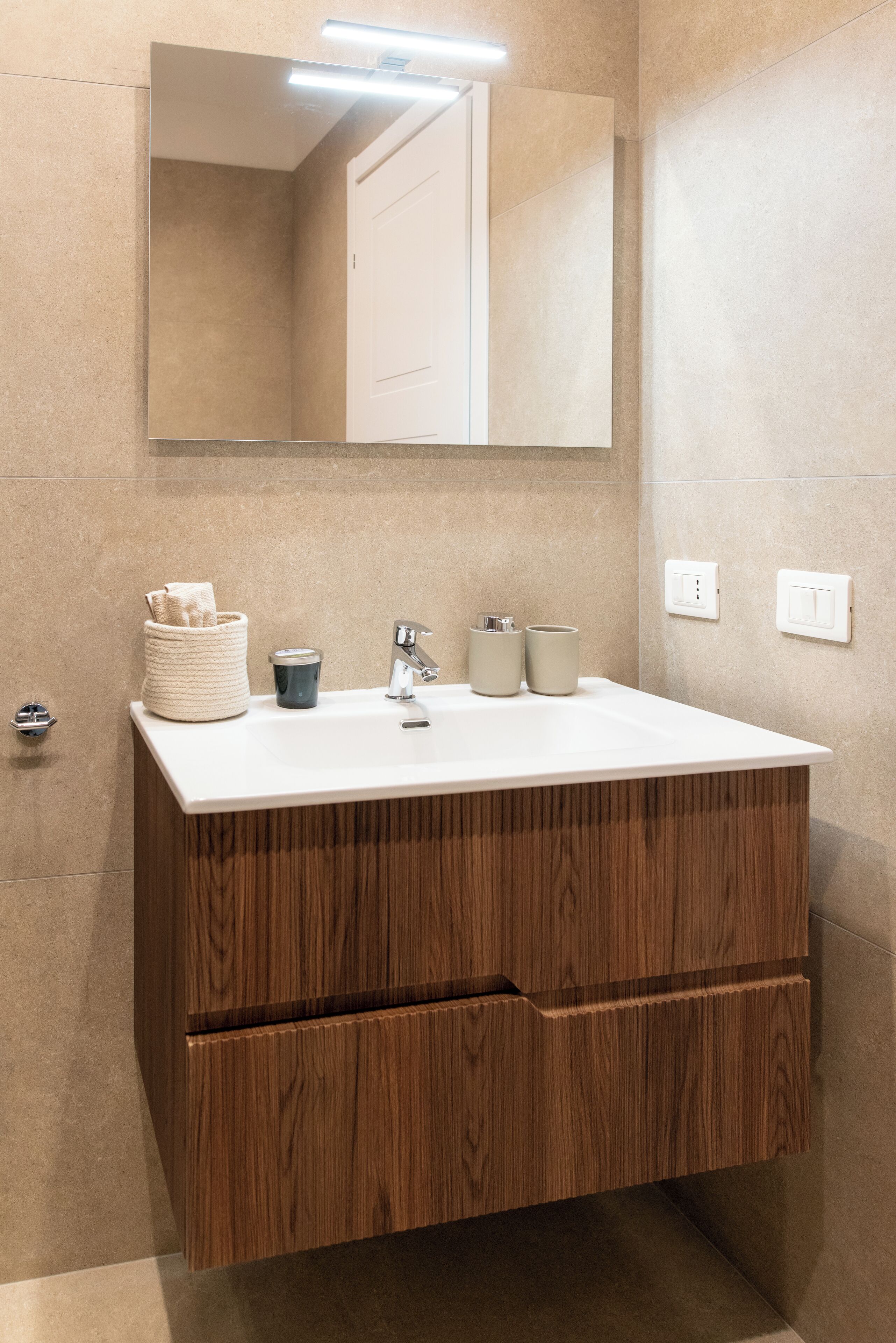 Un baño moderno con tocador de madera, un espejo grande y un lavabo blanco.
