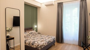 Una camera da letto con un letto, una scrivania, una sedia, uno specchio e una finestra con tende.