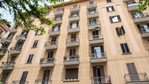 Un edificio a più piani con balconi, finestre con persiane e una facciata a griglia.