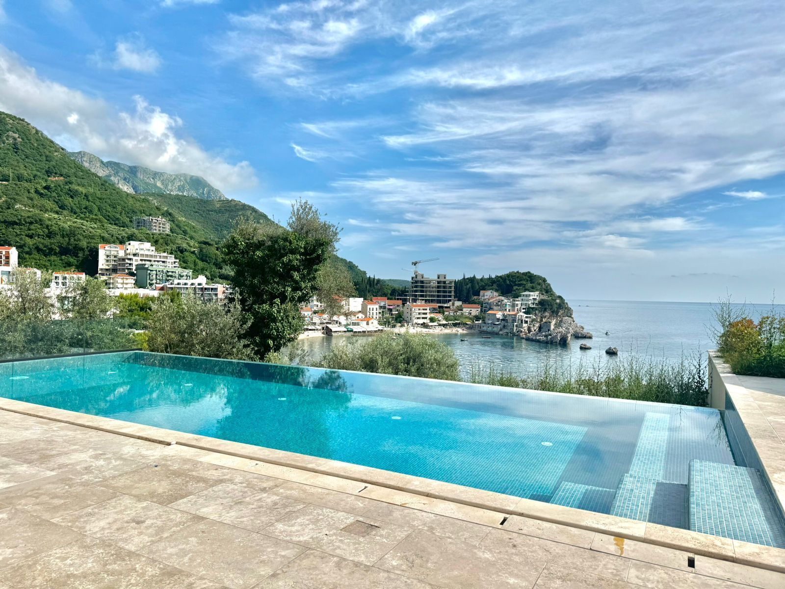 Una piscina con vistas a un pueblo costero y montañas al fondo.