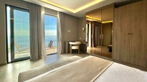 Una habitación de hotel moderna con una cama grande, un balcón con vistas al mar y un armario corredero.