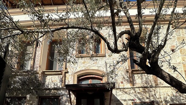Un edificio de piedra con puerta de madera, ventanas y entrada con tejas.