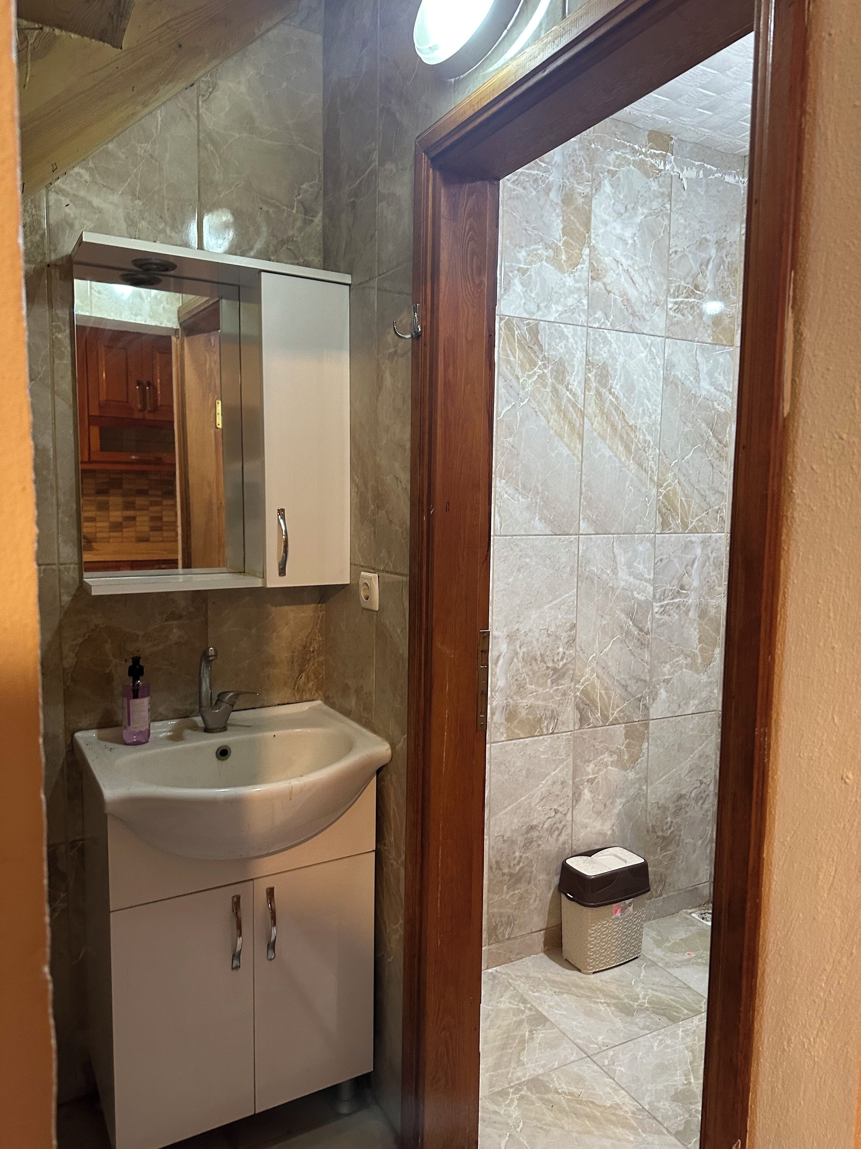 Un baño con lavamanos, espejo y armarios de madera.