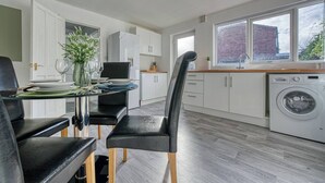 A modern kitchen with a dining area, white cabinets, a washing machine, and a large window. - City Centre*20%discount*Long Stay*Contractors (Hockley)