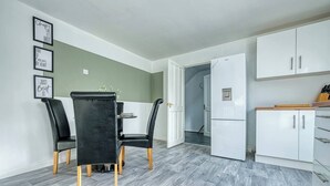 A modern kitchen with white cabinets, a black dining table with chairs, and a refrigerator. - City Centre*20%discount*Long Stay*Contractors (Hockley)