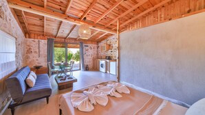 Un dormitorio con cama, sofá, mesa y una zona de cocina con lavadora.