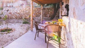 Un espacio de estar al aire libre techado con paredes de piedra, una mesa con sillas y una chimenea de piedra.