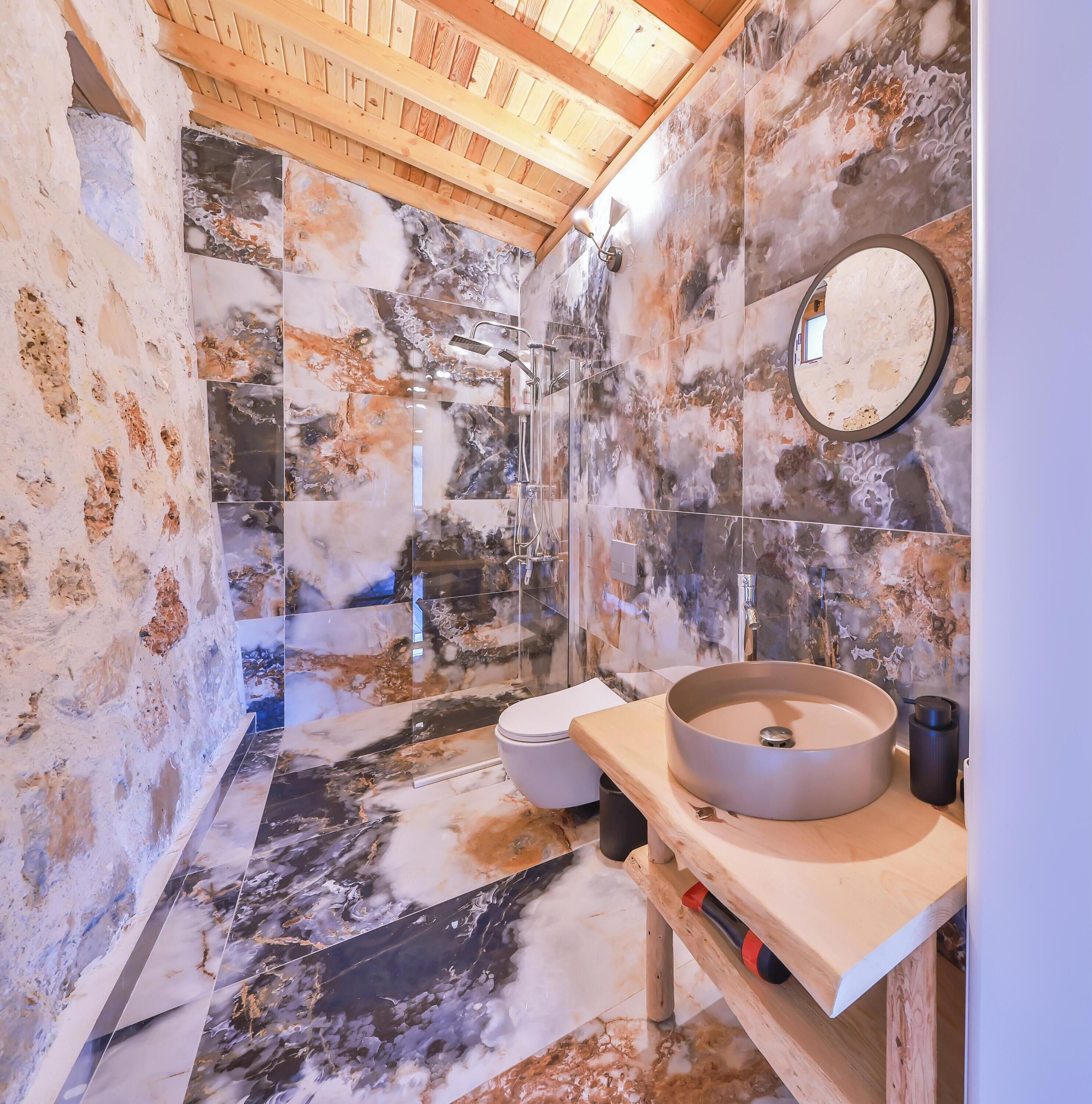 Een badkamer met een houten plafond, een rond wastafel en een toilet.