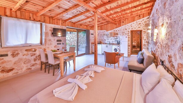 Una cabaña de madera acogedora con comedor, cocina y un dormitorio con cama grande y toallas.