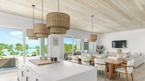 A modern kitchen with a large island, white cabinetry, and a view of the ocean.