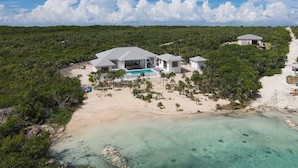 A beachfront property with a pool, multiple buildings, and lush greenery.