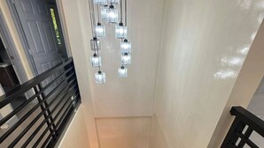 A modern staircase with a glass railing and a series of hanging lights. - GREAT PLACE TO STAY (San Nicolas)