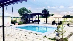 A swimming pool with a tiled deck, a covered seating area, and outdoor furniture. - GREAT PLACE TO STAY (San Nicolas)