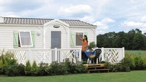 A white mobile home with a porch, a table, and chairs.