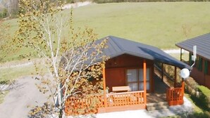 A wooden cabin with a porch and a satellite dish, surrounded by a grassy field and trees. - ZEcamping 4* familial animaux acceptés avec piscine et soirées animées (Lons)