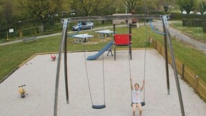 A playground with swings, a slide, and a sandbox. - ZEcamping 4* familial animaux acceptés avec piscine et soirées animées (Lons)
