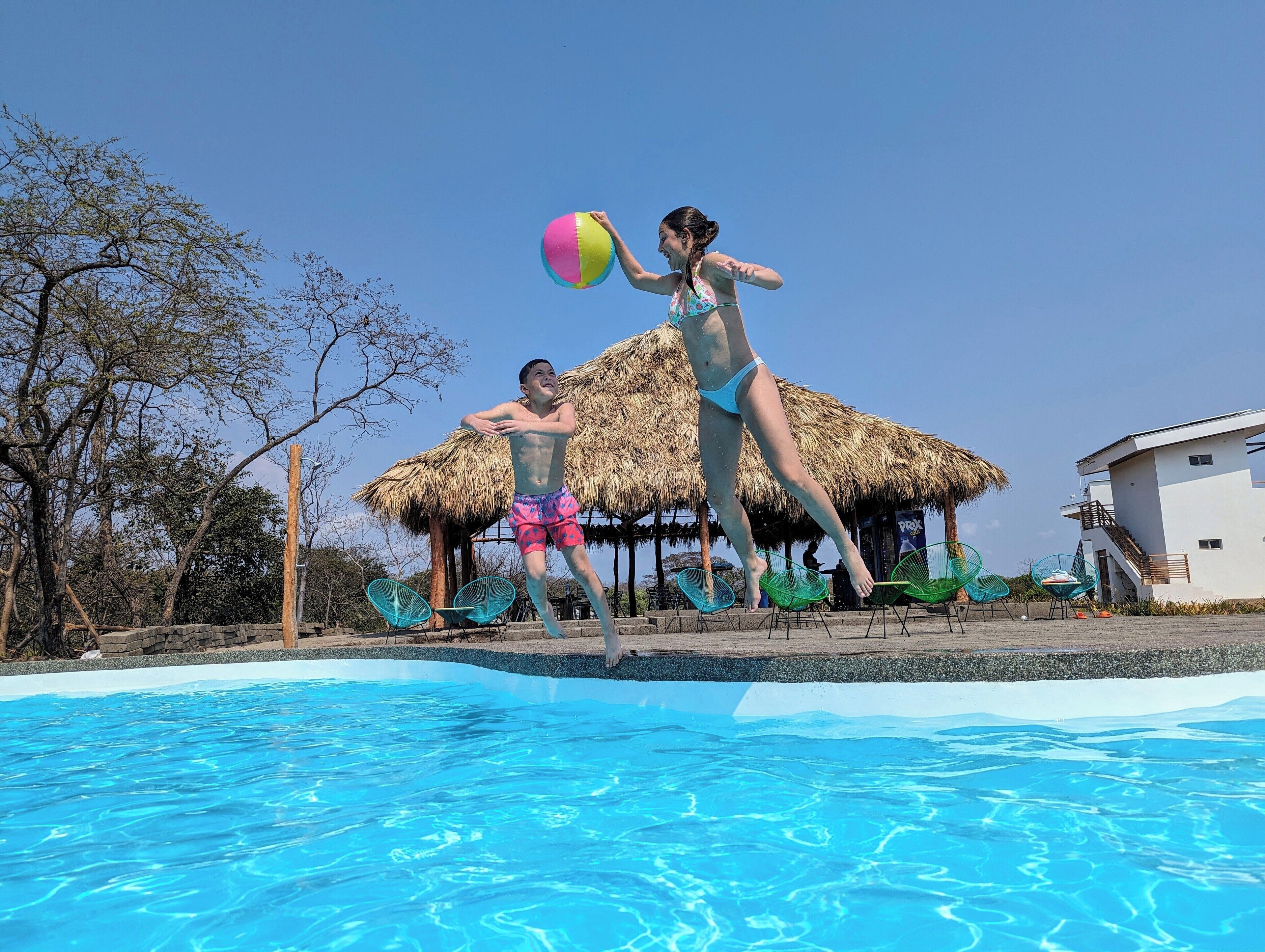 A swimming pool with a thatched-roof structure in the background.