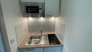 A compact kitchen with a built-in microwave, a sink with a faucet, and a stovetop.