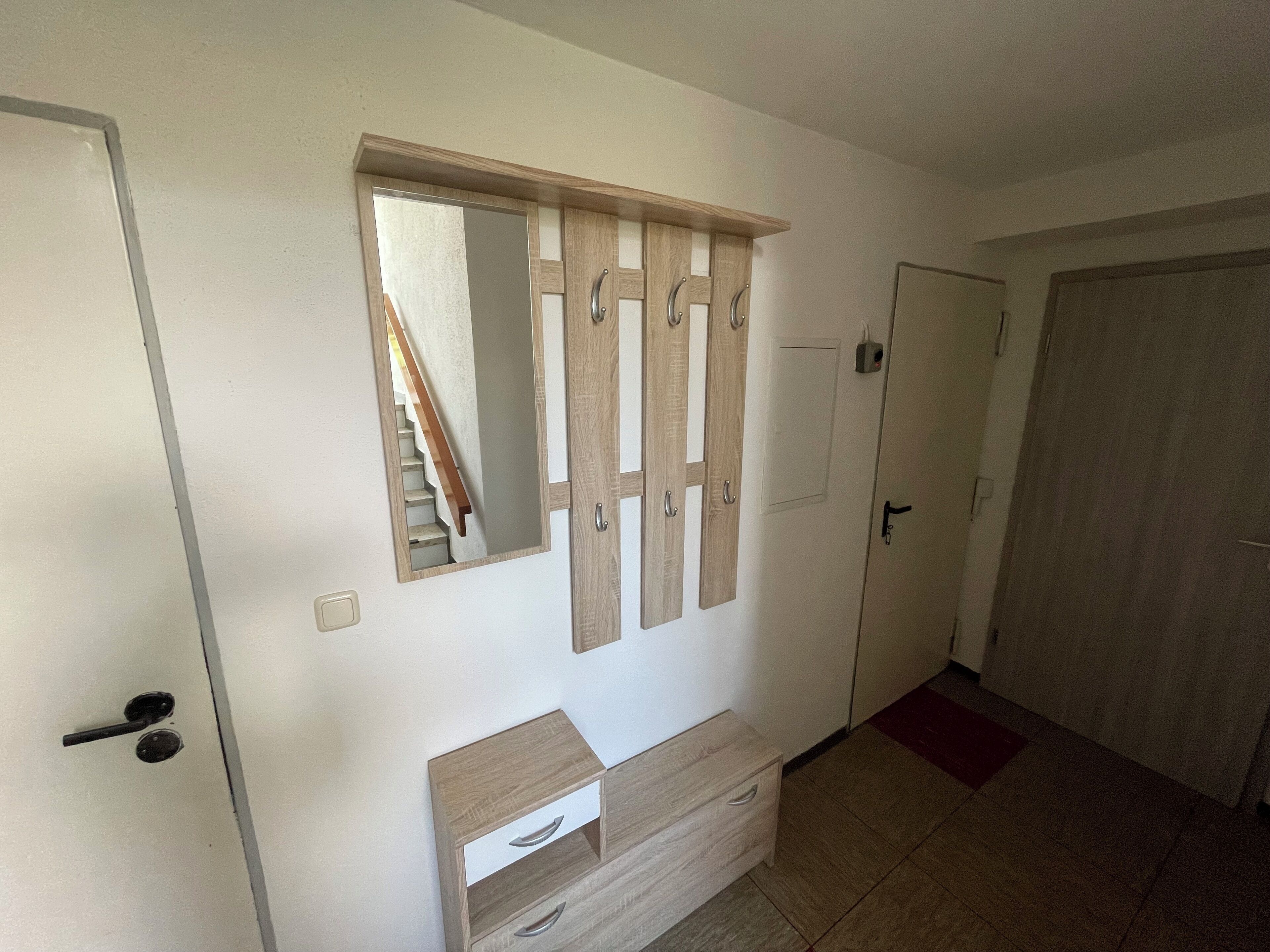 Un pasillo con un armario de madera, un espejo y una puerta.