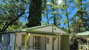 Une petite cabane à un seul étage, dotée d’une véranda, d’une table et de chaises.