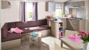 Un espacio habitable compacto con sofá, una pequeña mesa, kitchenette y comedor.