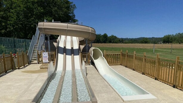Un parque acuático con un tobogán de agua grande y otro tobogán aparte.