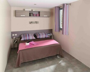 Cozy retreat with a single bed, striped pillows, and a shelf for personal touches.