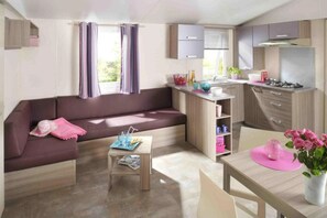 Un espacio habitable compacto con sofá, una pequeña mesa, kitchenette y comedor.