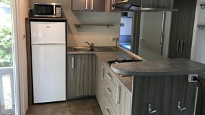 Una cocina compacta con microondas integrado, refrigerador, pileta y estufa.