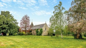 A church with a large lawn in front, surrounded by trees. - 4 bedroom accommodation in Hilmarton, near Calne (Hilmarton, near Calne)