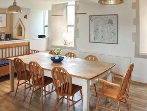 Un comedor con una mesa y sillas de madera, un cuenco azul con flores y un mapa en la pared.