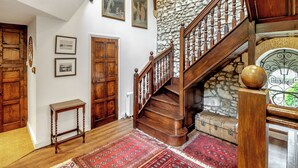 A wooden staircase with a stone wall, wooden doors, and a red patterned rug. - 4 bedroom accommodation in Hilmarton, near Calne (Hilmarton, near Calne)
