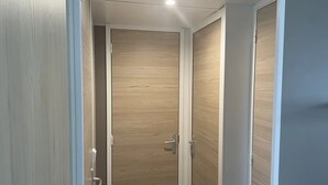 A narrow, wooden-paneled room with a door and a light fixture on the ceiling.