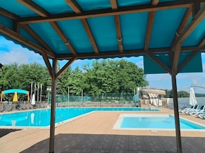 Un espace piscine couvert, doté de chaises longues et offrant une vue sur les arbres.