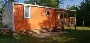 Eine kleine Holzhütte mit einer Terrasse und einem Fenster.