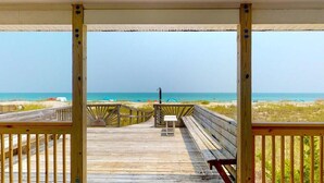 A wooden deck with a view of the beach and ocean.