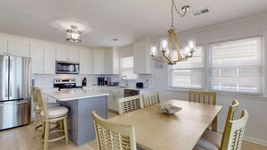 A modern kitchen with white cabinetry, stainless steel appliances, and a central island with seating.