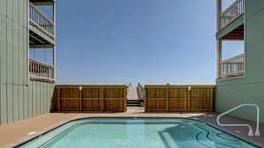 A clear swimming pool with wooden deck and railings, surrounded by a building with balconies. - Sands 4 3-A-2 bedroom 2 bath, 3rd floor condo with sweeping views from the Master and living room (Carolina Beach)