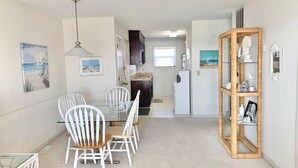 A compact kitchen with a refrigerator, a dining table with chairs, and a small island with a sink. - Sands 4 3-A-2 bedroom 2 bath, 3rd floor condo with sweeping views from the Master and living room (Carolina Beach)