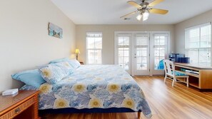 A bedroom with a bed, a desk, a chair, and a ceiling fan.