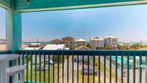 A balcony with a view of a residential area, including houses and a road. - Salty Shamrock, modern and spacious 2 bedroom, 2 bathroom condo, with ocean views (Carolina Beach)