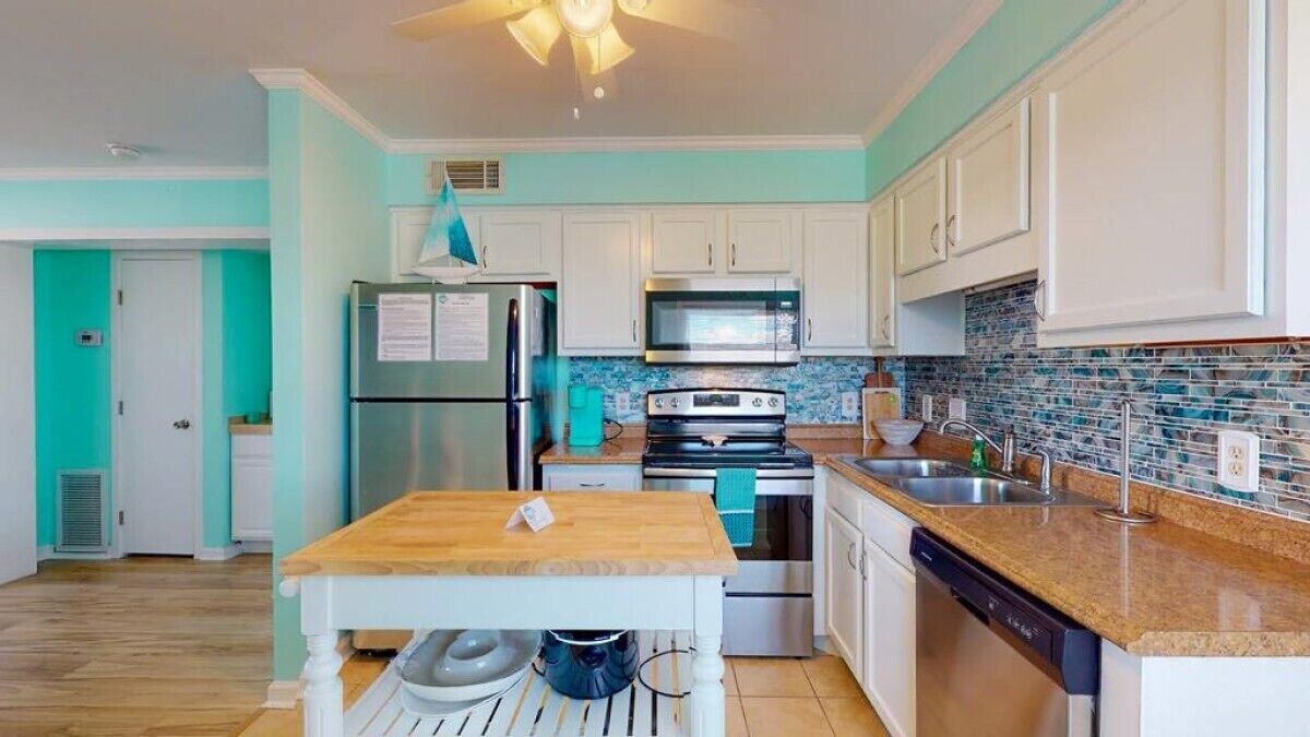 A kitchen with white cabinets, a stainless steel refrigerator, a microwave, an oven, and a dishwasher.