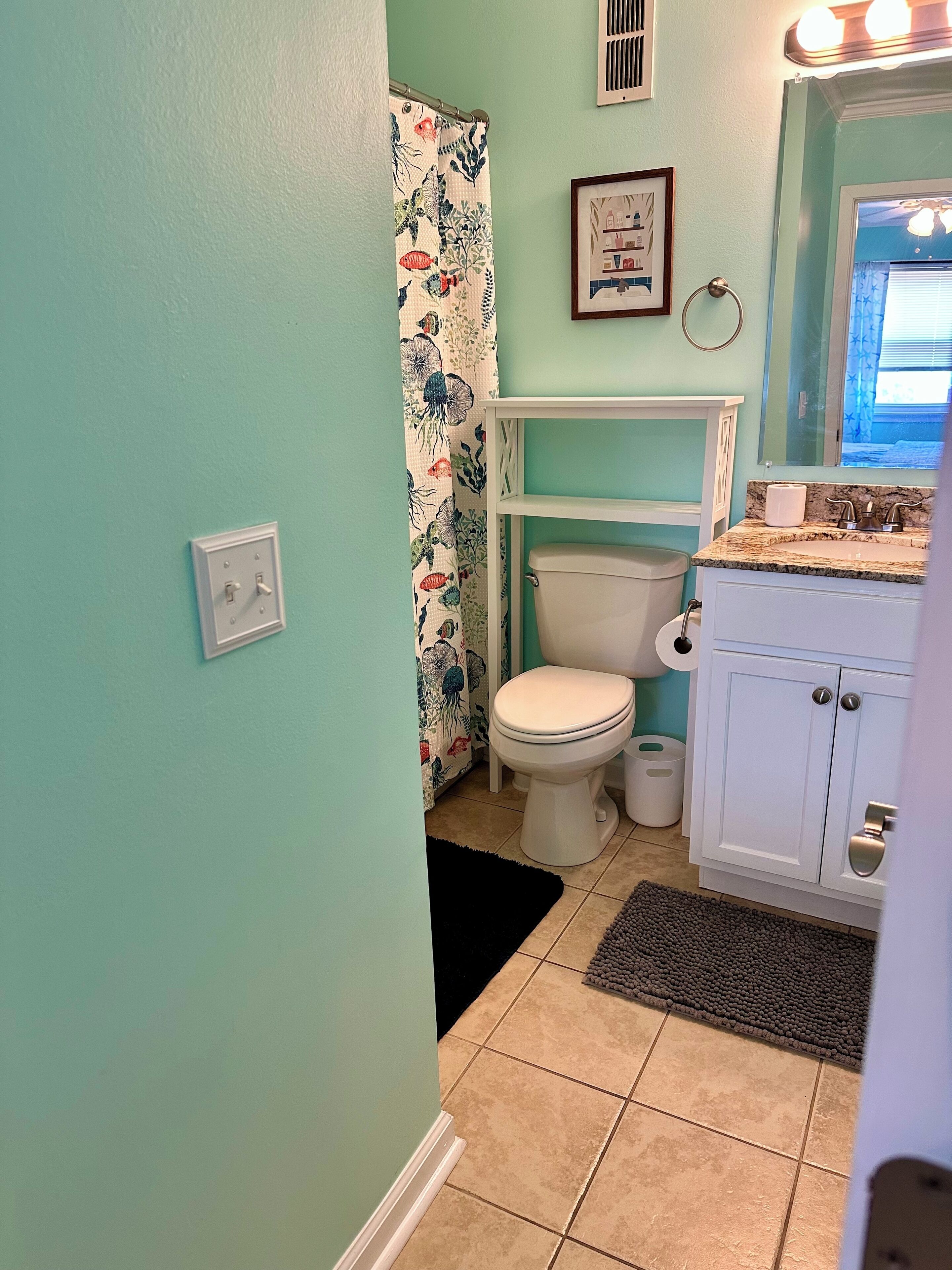 Un baño con inodoro, lavamanos y cortina de ducha.