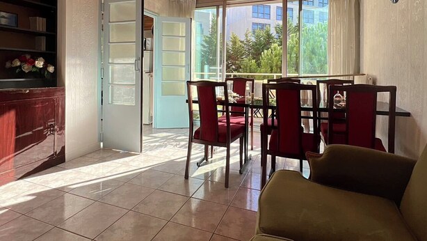 Un comedor con techo de madera, una mesa de comedor con sillas rojas y vistas a zonas verdes.