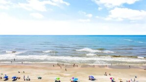 A beach with people, umbrellas, and a clear sky.