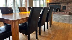 A wooden dining table with black chairs in a room with exposed brick walls and a fireplace.
